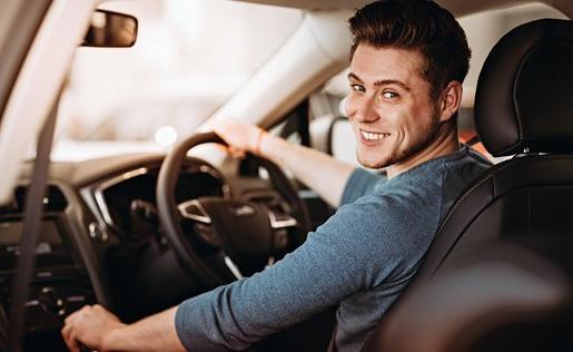 A young man sitting behind the wheel of a car.